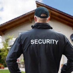 Rear View Of A Male Security Guard Standing Outside The House